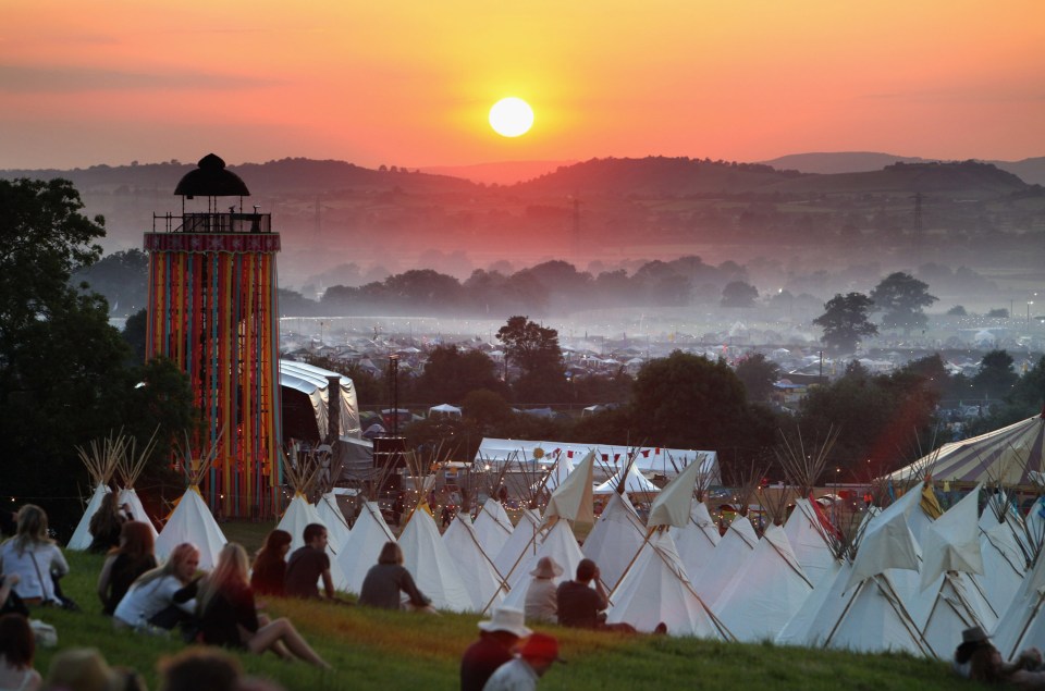 Glastonbury fans gather to watch the sunset on a hill above the tipi field in 2009