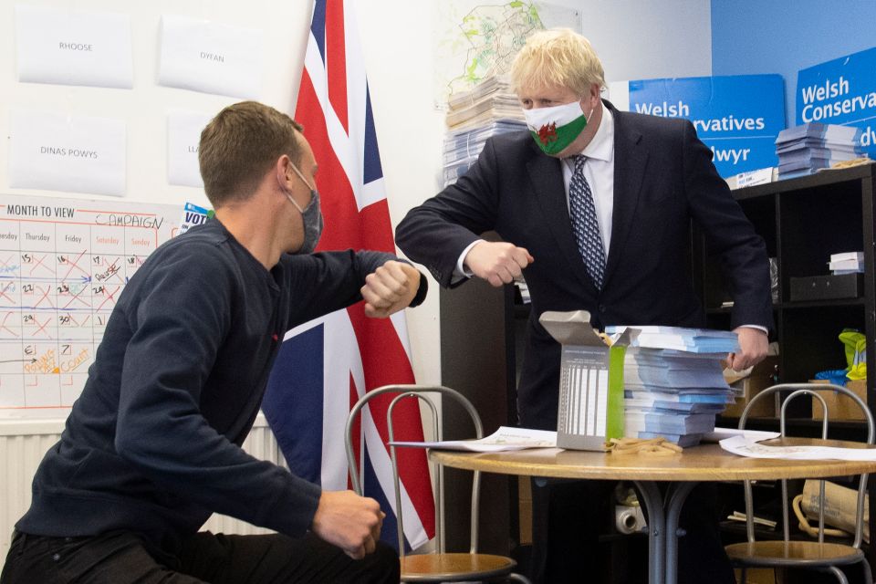 Boris Johnson touches elbows with a campaigner during a visit to Barry, Wales