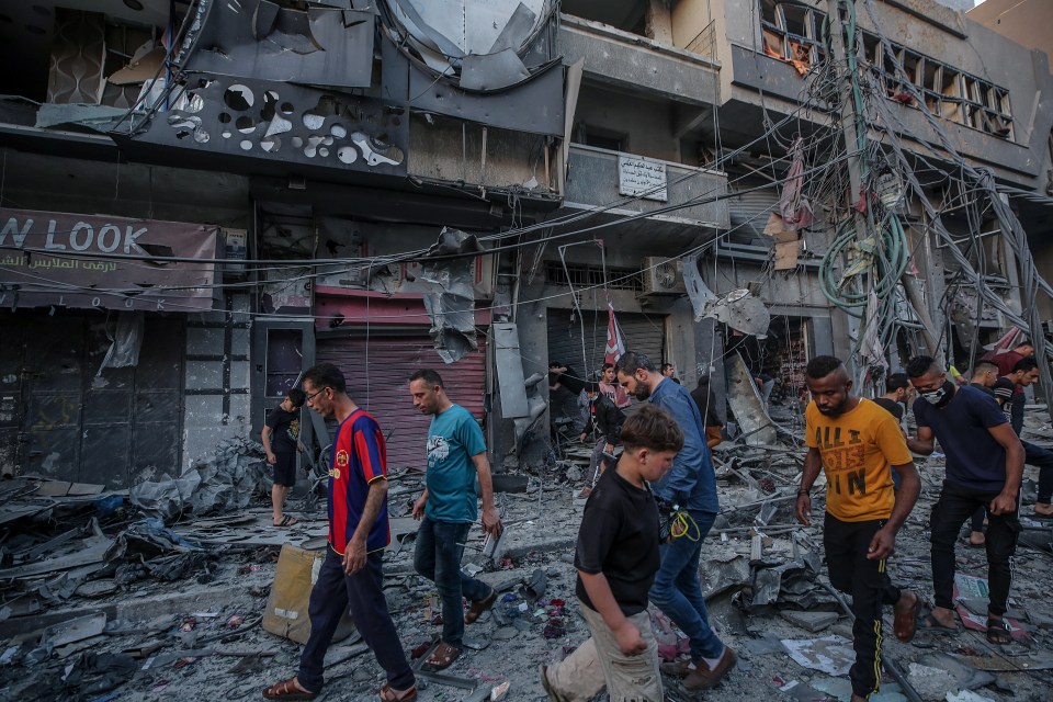  Palestinians inspect the rubble of the destroyed Al-Shorouq tower after an Israeli strike in Gaza City, May 2021