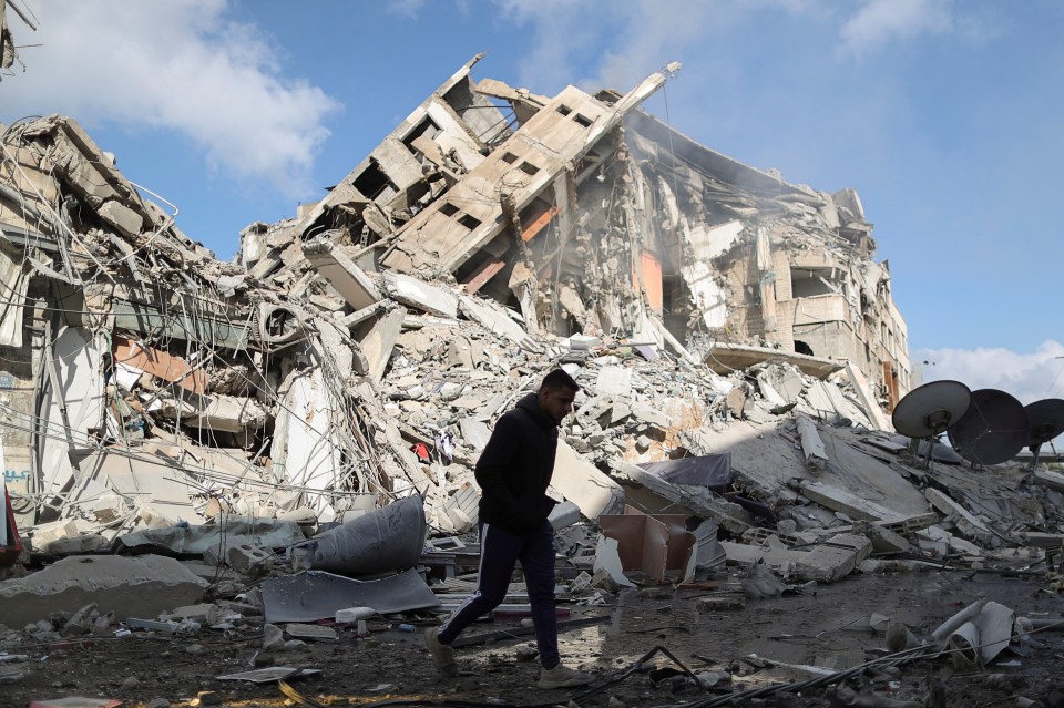 A Palestinian man walks past the remains of a building destroyed by Israeli air strikes in Gaza