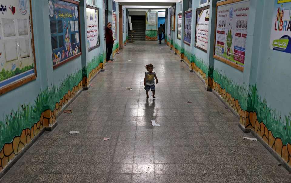 A little Palestinian girl walks down a hall in a UN school in Gaza where her family are sheltering after fleeing their home