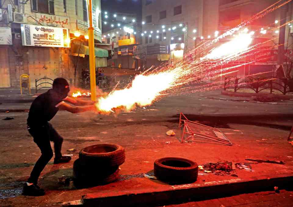 A Palestinian protester launches flares amid clashes with Israeli soldiers in the occupied West Bank