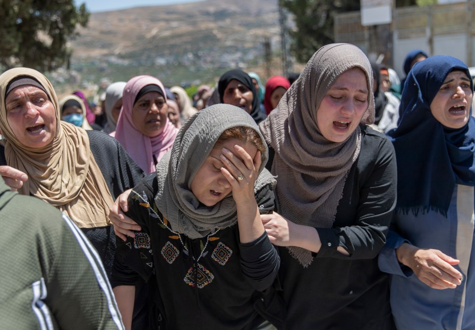 Palestinian mourners cry during funeral for a girl, 20, shot dead in village