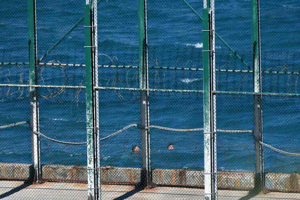 Two of the migrants in the sea swimming past the border fence