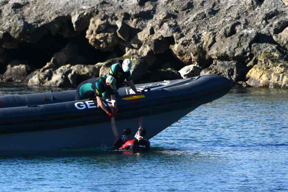 Police helping one of the migrants out the water