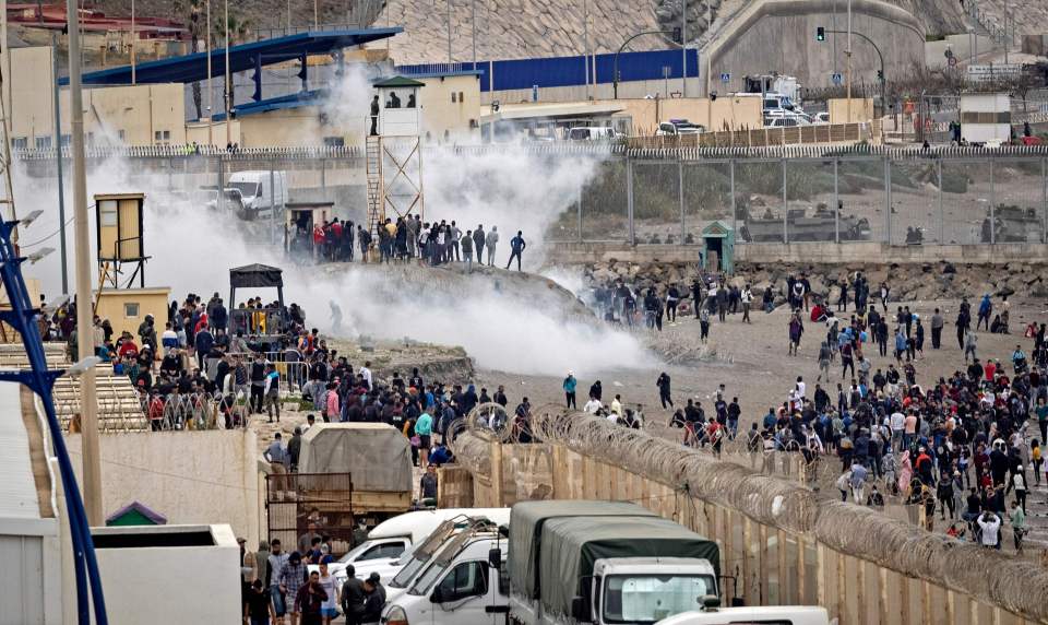 Smoke fills the air as Moroccan migrants rally by a border fence