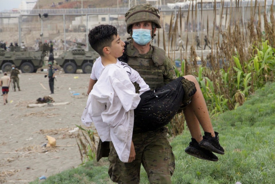 An exhausted migrant is helped to safety in Ceuta