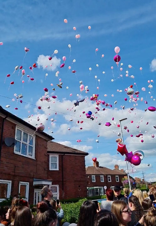 Mourners let pink and white balloons off into the sky in memory of the toddler