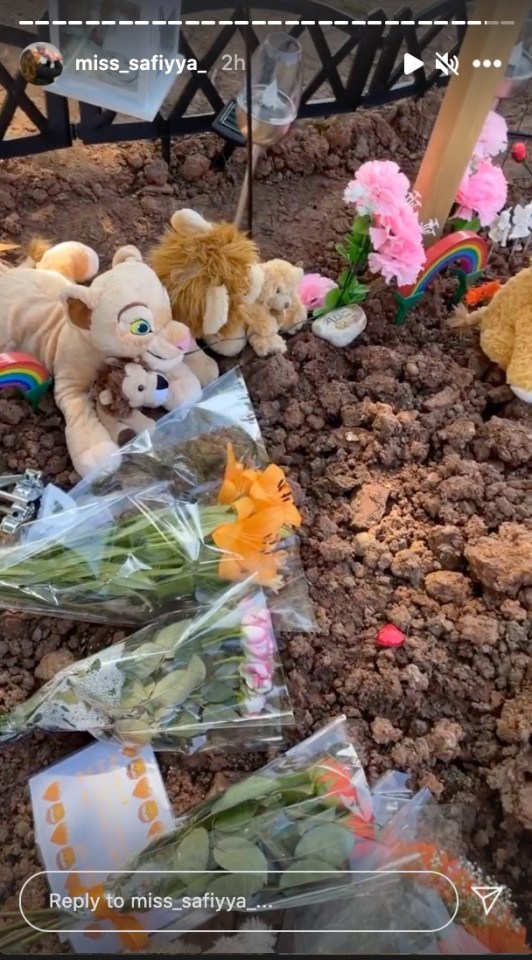 The graveside is covered with flowers and cuddly toys