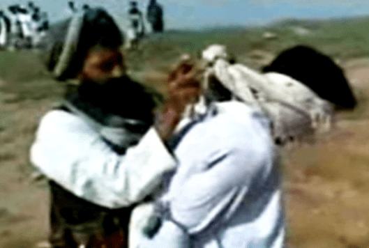 Taliban militant ties a blindfold round a man's head before he is stoned for 'adultery'