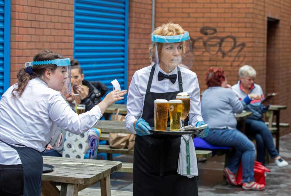 Staff wearing PPE serve people enjoying a drink in Belfast city centre