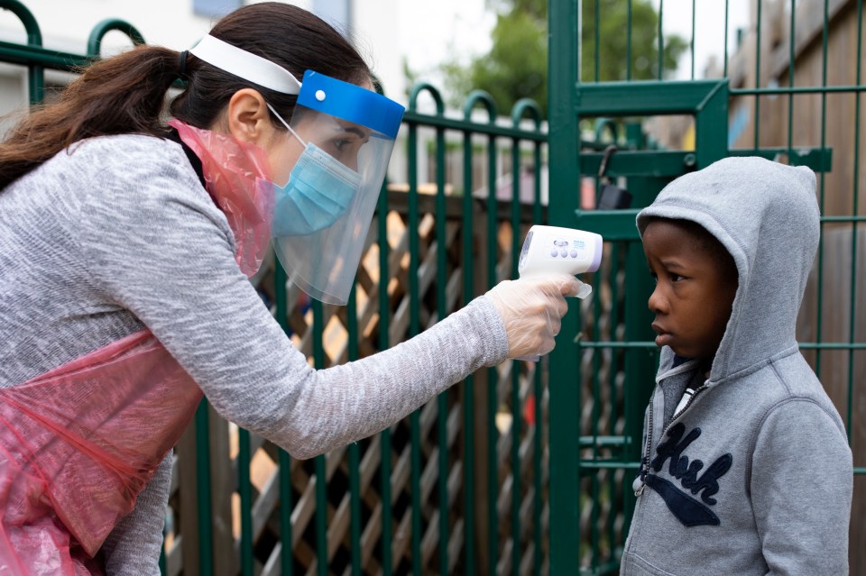 A member of staff wearing PPE takes a child's temperature at the Harris Academy's Shortland's school in London