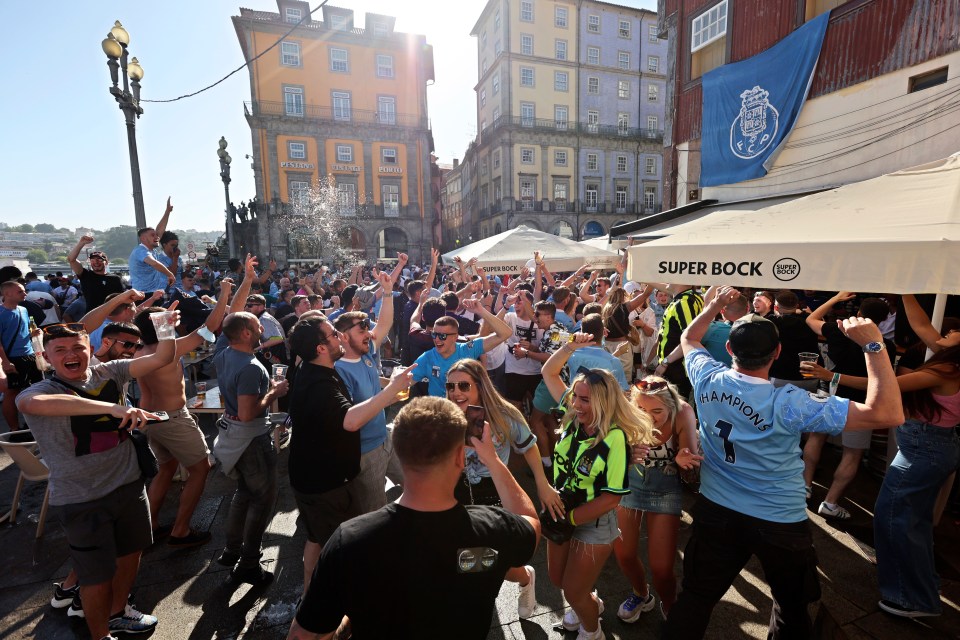 Manchester City supporters drink and chant by the Douro river bank in Porto, Portugal