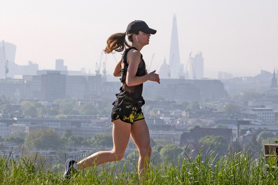 A jogger is seen running at Hampstead Heath with London in the background