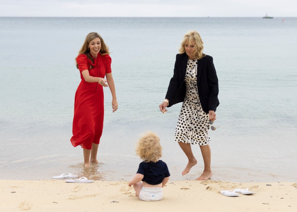 Carrie and Jill paddle in the sea as baby Wilf looks on