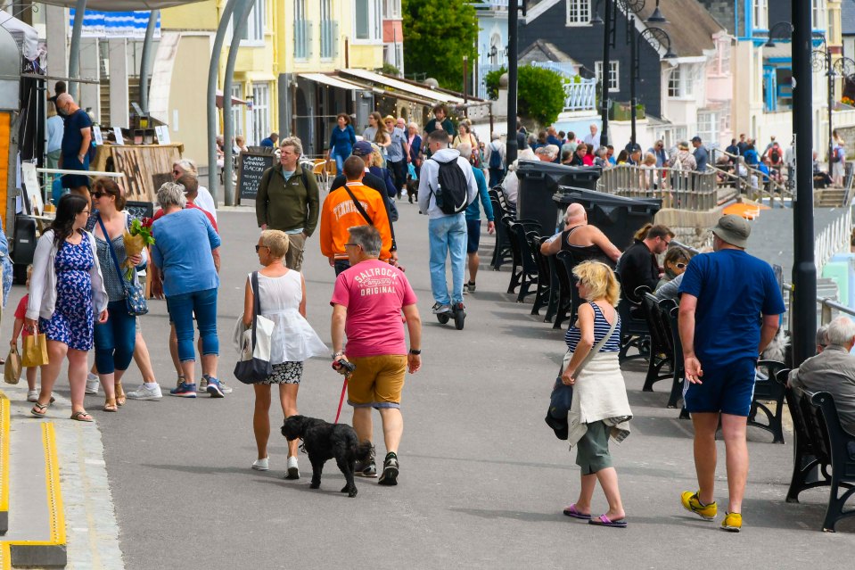 Visitors on the seafront enjoying the warm hazy sunshine in Lyme Regis, Dorset