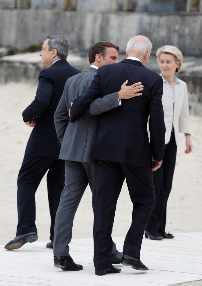 Emmanuel Macron and Joe Biden embrace as they walk up the beach at Carbis Bay