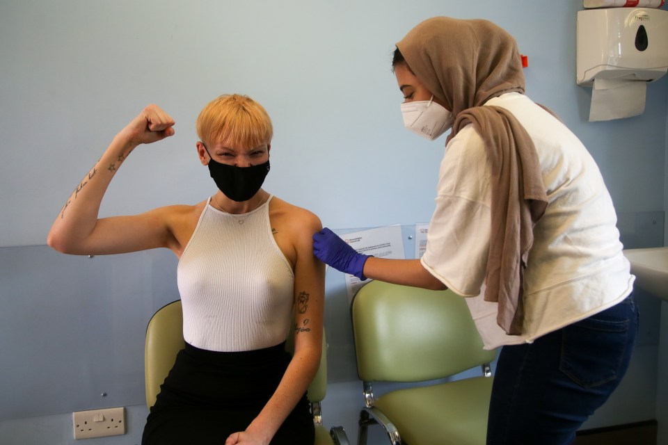 Charlotte Jane Meekings gestures after vaccinator Nishat Ahmed administered the first dose of Pfizer Covid-19 vaccine at a vaccination centre in Haringey, north London