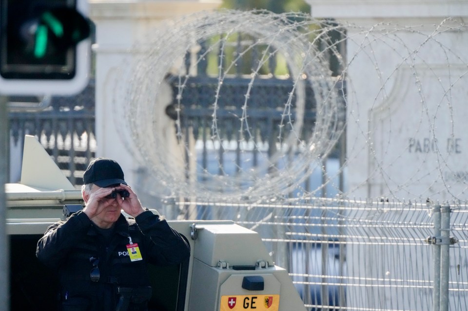 A police officer looks through a binoculars to guard the area