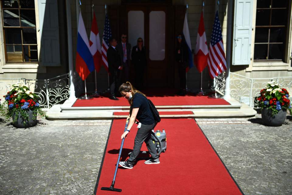 A staff member vacuums the red carpet at the Villa La Grange ahead of the US-Russia summit in Geneva