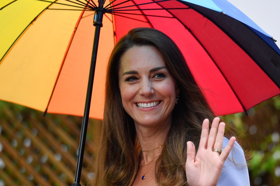 Kate flashes a smile at the camera after swapping for a rainbow umbrella