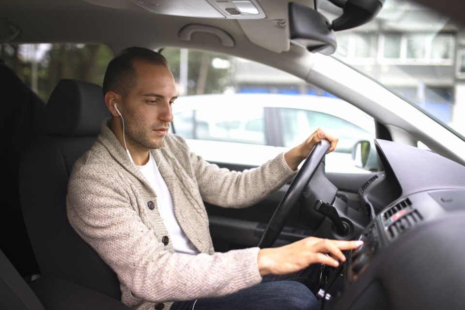 a man wearing ear buds is listening to music in his car