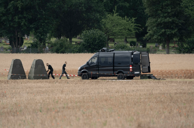 A police van in a field with the fenced off allotments in the background during the dig in Germany last summer