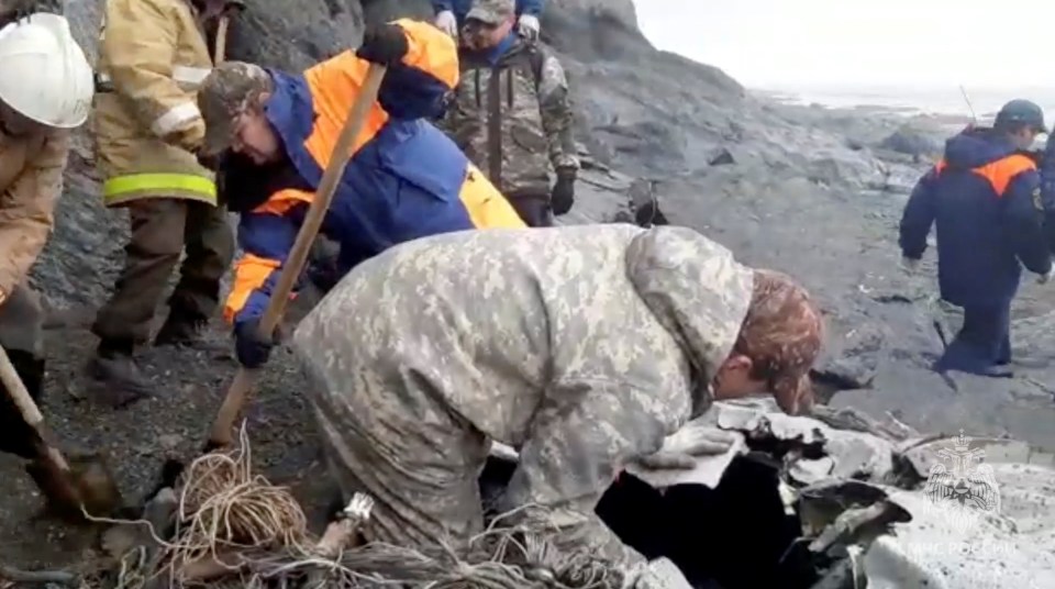 Specialists of the Russian Emergencies Ministry are seen at the crash site at the bottom of the cliff