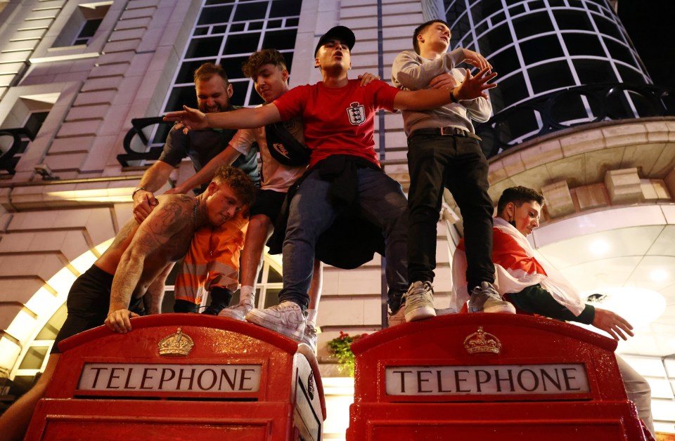 A group of lads climbed on top  of telephone boxes in Piccadilly Circus