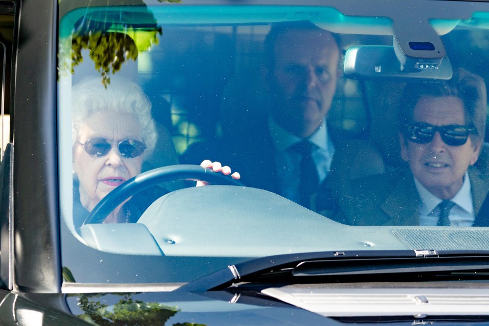 The monarch was seen wearing a white top adorned with pink roses and a green gilet as she drove around Wood Farm Cottage on the estate