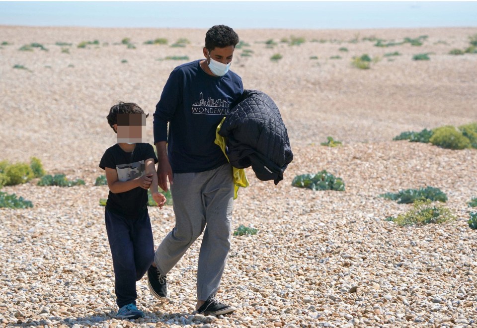 A man holds his son's hand after arriving on the Kent beach