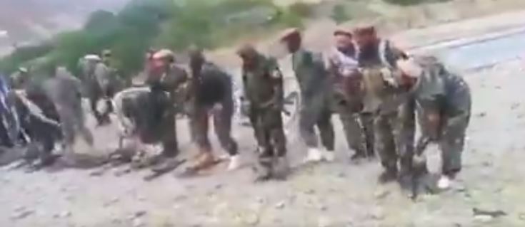 Afghan soldiers line up to lay their guns on the ground