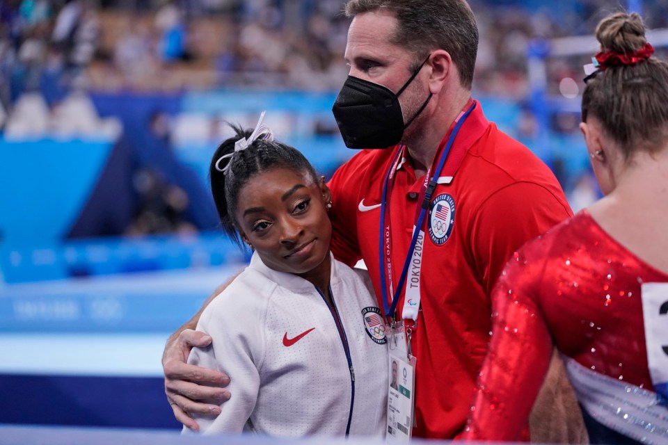 Biles is embraced by her coach after withdrawing from the team event