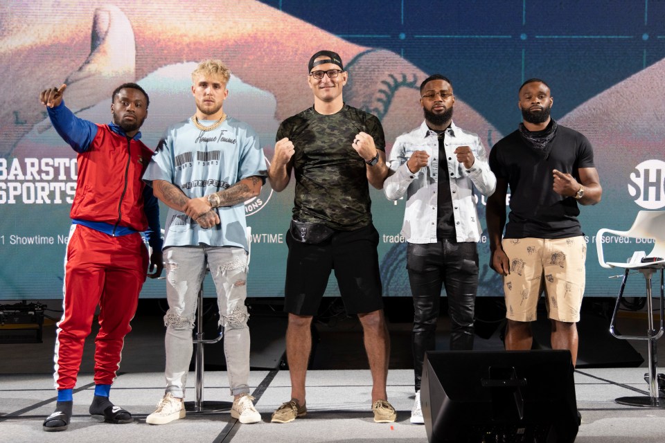 Jake Paul on stage with Stipe Miocic, middle, with Tyron Woodley, far right