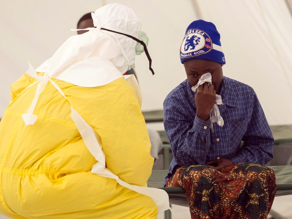 a man wearing a blue chelsea hat wipes his face