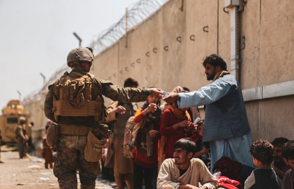 A soldier hands out water to evacuees at Kabul airport