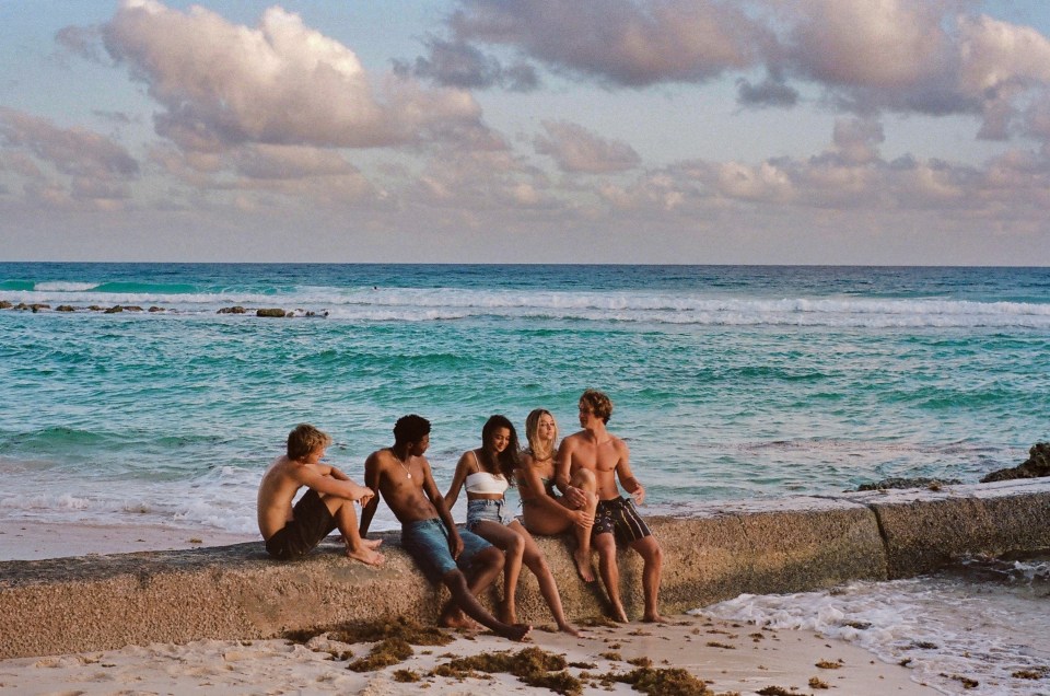 a group of people sitting on a rock near the ocean