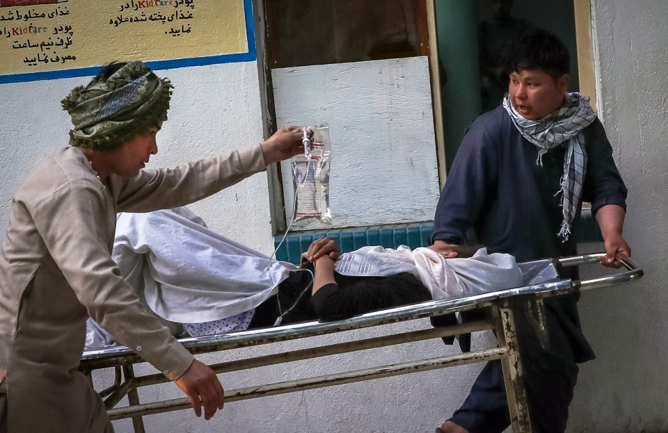 People carry an injured girl into a hospital after an explosion at a school in Kabul