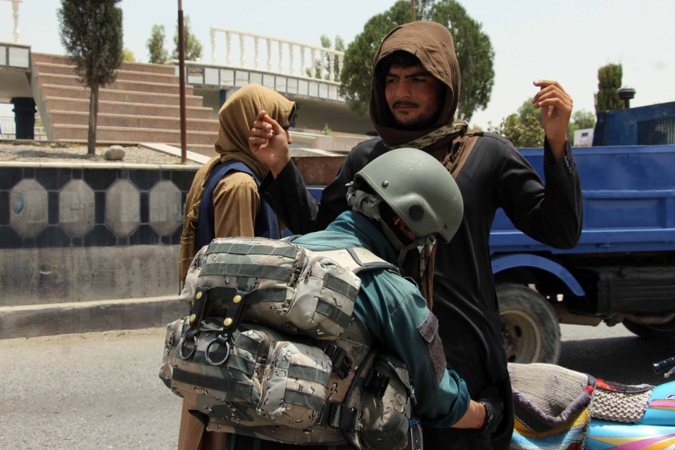 Afghan security officials check people on a roadside checkpoint in Kandahar