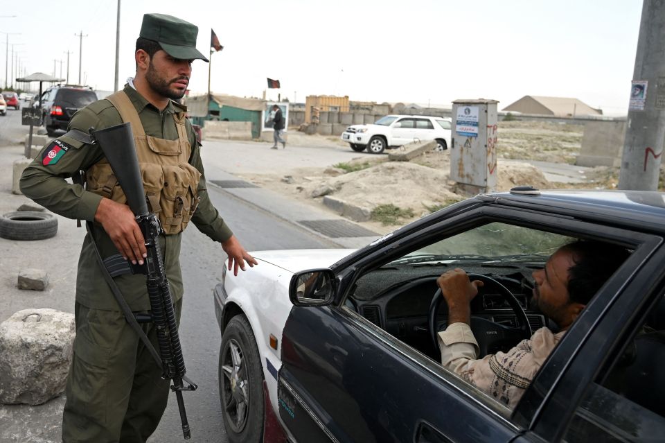 An Afghan policeman speaks to a commuter at a checkpoint along the road in Kabul on August 14, 2021