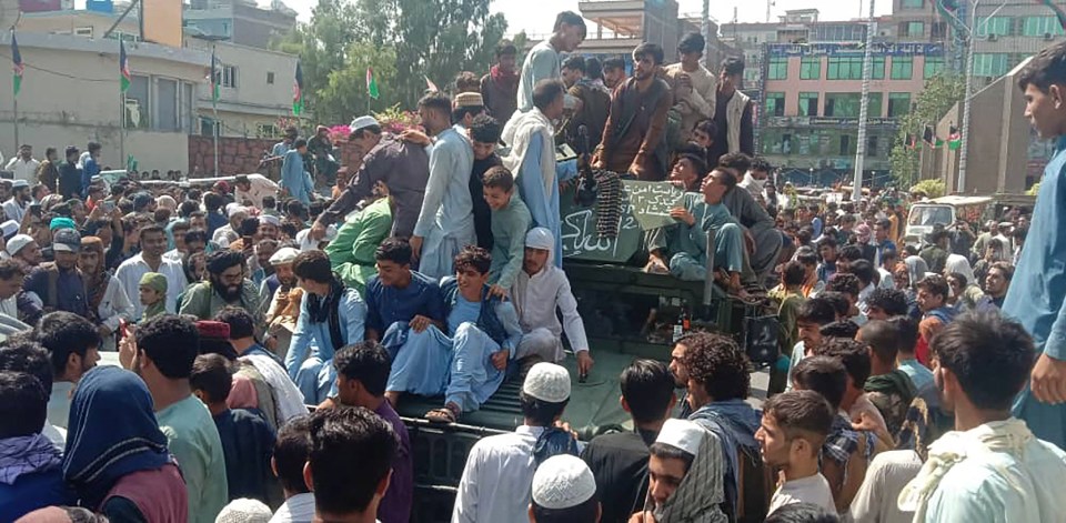 Taliban fighters and locals sit on an Afghan National Army humvee vehicle in Jalalabad