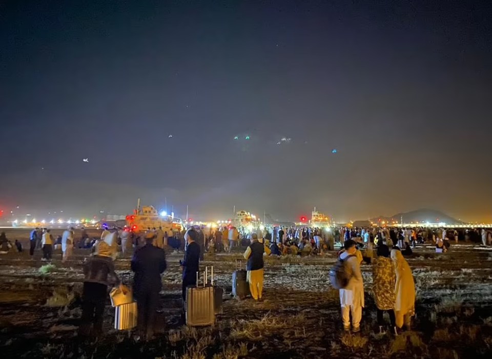 People waiting with suitcases near Kabul Airport’s runway