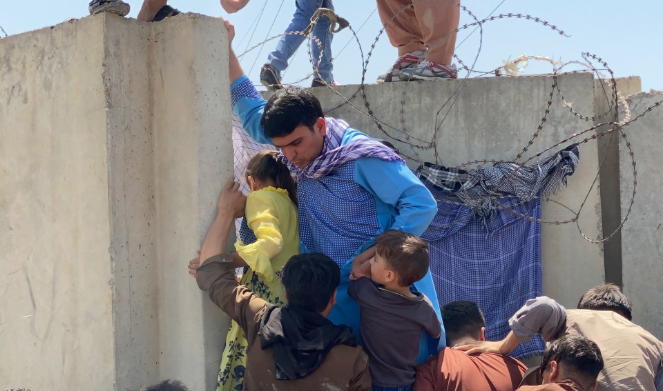 People scrambling through barbed wire to get into the airport