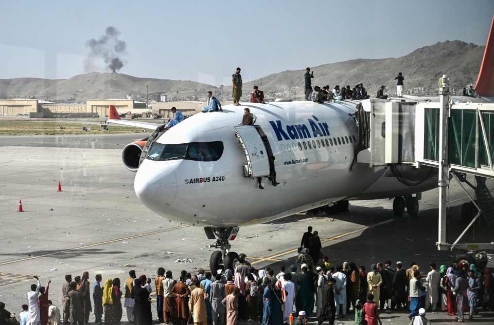 Afghans climb over a plane as they desperately try to escape