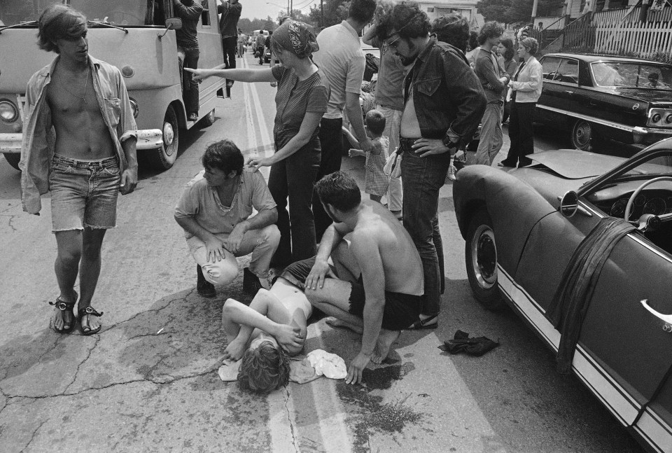 A man lays on the ground as cars snarl in the eight hour traffic jams to Woodstock