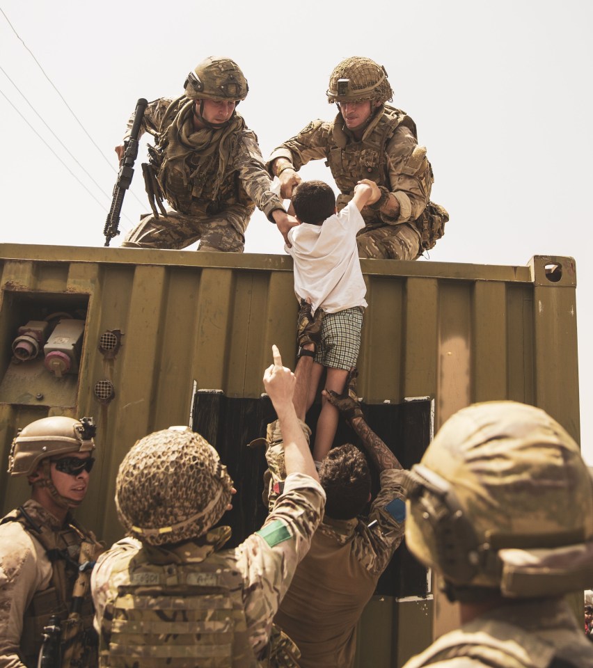 Troops help a child during the evacuation efforts at Kabul airport