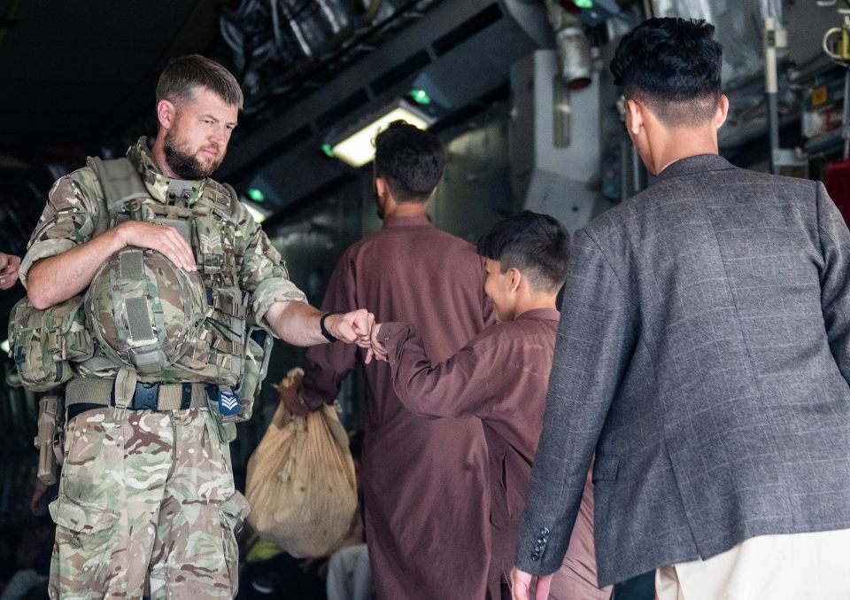 A member of the UK Armed Forces fist-bumping a child evacuee at Kabul airport