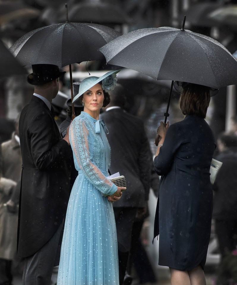 The Duchess Of Cambridge shelters under Prince William's umbrella at the First Race as the horses parade in the ring at Royal Ascot