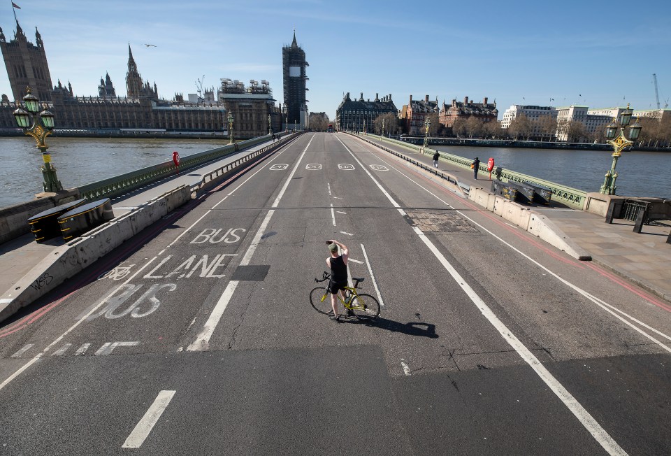 A cyclist stops in the middle of a deserted Westminster Bridge to take a pic after PM Boris Johnson had announced that the UK would lockdown due to the pandemic