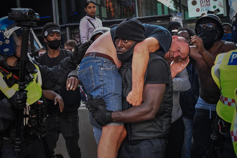 Black Lives Matter protester Patrick Hutchinson carries an injured suspected far-right counter-protester to safety near London's Waterloo Station following the horrific death of George Floyd in Minneapolis Police custody